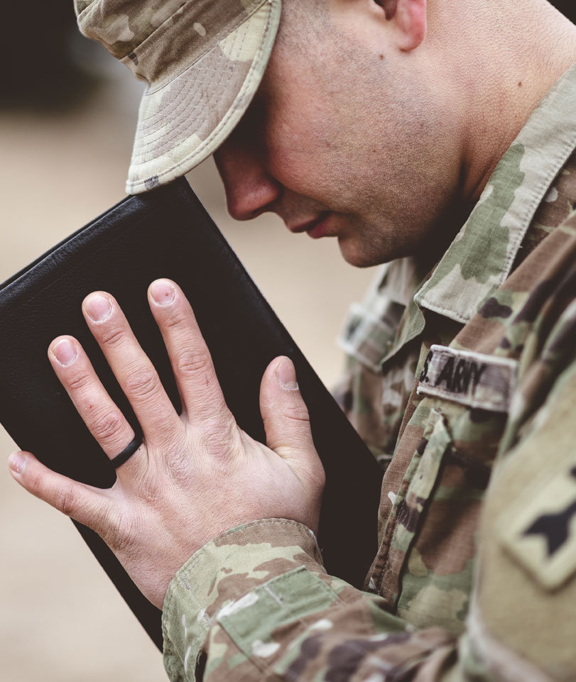 Prayerful soldier holding a bible
